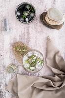 Glass with carbonated alcoholic drink with rosemary and ice in glass on table top and vertical view photo