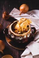 Homemade onion soup with cheese croutons in a pot on the table vertical view photo