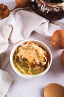 French onion soup with baked cheese bread in a bowl on the table vertical view photo