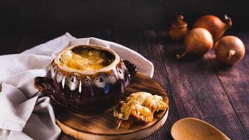 French onion soup with melted cheese and croutons in a pot on the table web banner photo