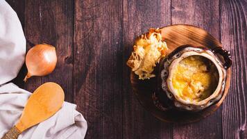 Homemade onion soup with cheese croutons in a pot on the table top view web banner photo