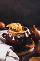 French onion soup with melted cheese and croutons in a pot on the table vertical view photo