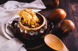 Homemade onion soup with cheese croutons in a pot on the table photo