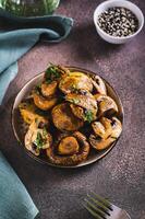 Homemade grilled mushrooms with herb on a plate on the table vertical view photo