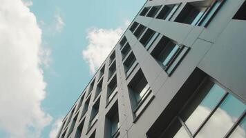 een deel van de facade van een modern bedrijf centrum gebouw is een onderkant boven visie. de lucht weerspiegeld in de ramen van de gebouw. video