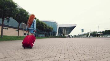 vrouw wandelen met bagage. de meisje gaat Aan een reis en wandelingen naar de luchthaven. een zakenvrouw wandelingen naar beneden de straat met bagage in haar hand- en onderzoekt de stad. video