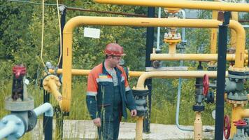 ingeniero a el gas distribución complejo hace un desvío a el gas estación. un empleado de un gas producción empresa trabajos a un gas producción estación video