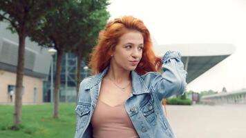 portrait de une jolie caucasien femme en marchant avec souriant et à la recherche à le caméra. fille sur le rue sur une Contexte de moderne intérieurs souriant à le caméra. video