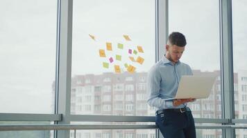 Young successful businessman in the office by the window working with a laptop. The man solves business strategic tasks. video