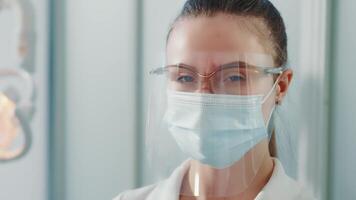 retrato do uma médico dentro uma protetora mascarar e óculos. fêmea médico fechar acima. jovem médico olhando às a Câmera. video