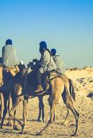 Beduins leading tourists on camels at short tourist tour around the beginning so called Doors of Sahara desert photo