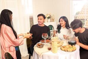 musulmán familias obtener juntos mientras celebrando idul Fitri por Bebiendo y comiendo foto