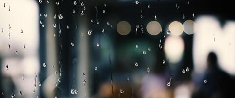Rain drop on window glass of coffee shop and blurry city life background. Rainy season and blurry people city day life or bokeh night lights outside window. Coffee shop window covered with rain water photo
