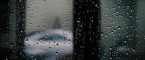 Rain drop on window glass of coffee shop and blurry city life background. Rainy season and blurry people city day life or bokeh night lights outside window. Coffee shop window covered with rain water photo