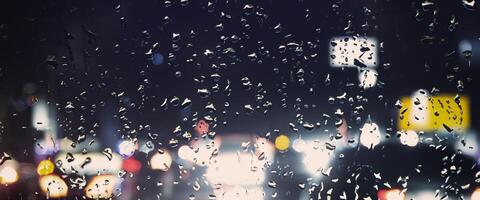 Driving in raining. Rain on car windshield or car window in rainy season and blurry traffic road in background. Rain drops on car mirror. Road in rain. Drizzle raining decreases driving visibility. photo