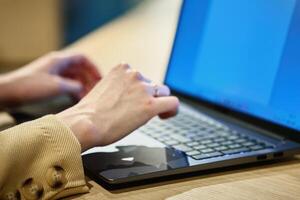 Female hand typing on laptop keyboard in cafe photo