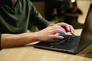 Male hand typing on laptop keyboard in cafe photo