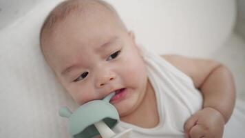 en bebis är gråt medan innehav en leksak. de bebis är bär en vit skjorta video