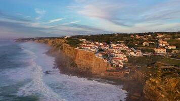 branco casas do azenhas Faz mar Vila dentro Portugal às pôr do sol, falésias e ondas do atlântico oceano. aéreo visualizar. zangão movimentos para trás e para cima video