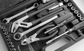 Black case with separated slots in shape of variety repairing hand tools angle view monochrome stock photo