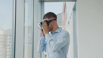 schließen oben jung Mann Sitzung beim ein Schreibtisch im das Büro Verwendet erweitert Wirklichkeit Brille zu Arbeit auf Geschäft Projekte im verschiedene Felder. Arbeit im virtuell Wirklichkeit video