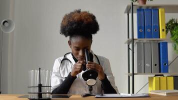 African female scientist doing some research and looking through a microscope in laboratory video