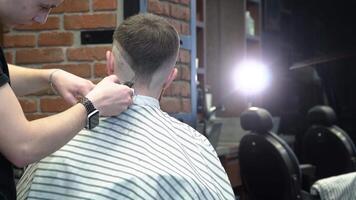 peluquero hace un Corte de pelo diseño en el espalda de el clientela cabeza video
