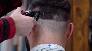 Barber cuts a hair trimmer on the back of the client's head. Close up view. Caucasian video