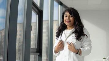 jong Indisch medisch leerling Bij de kliniek in oefening. vrouw dokter in een wit jas met een stethoscoop. video