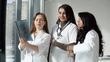 Three women doctors of different races analyze the X-ray video