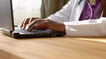 Close up of hands of african woman doctor working on laptop in clinic video