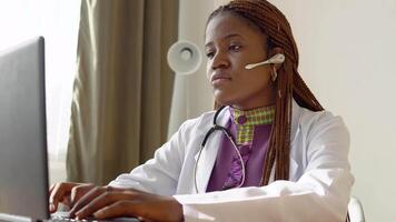 joven africano americano hembra médico trabajando en ordenador portátil en clínica video