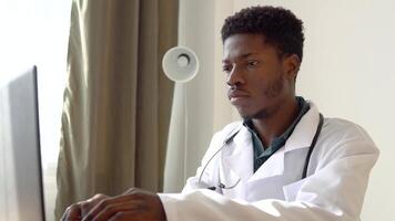 Young african american male doctor working on laptop in clinic video