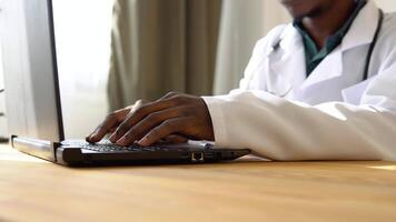 Close up of hands of african american male doctor working on laptop in clinic video
