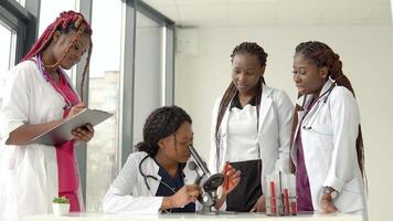 Young african doctors perform a blood test with a microscope while one of them takes notes video