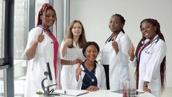 een groep van jong medici zittend en staand Bij een tafel tonen klasse video