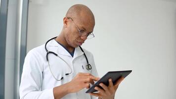 joven afro americano masculino médico médico haciendo notas en tableta video