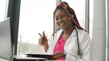 Young african american woman doctor with red hair having chat or consultation on laptop video