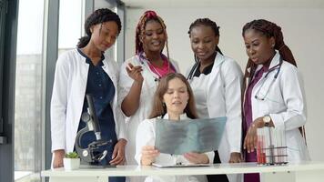 cinq médecins de différent les courses examiner un radiographie tandis que permanent à une table video