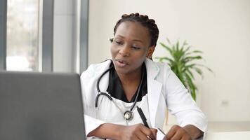 African woman doctor having with headset chat or consultation on laptop video