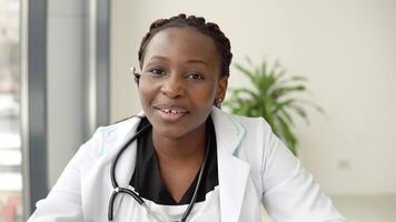 Young african american woman doctor having chat or consultation on laptop looking directly to the camera video