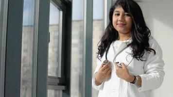 Young Indian medical student at the clinic in practice. Female doctor in a white coat with a stethoscope. video