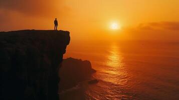 AI generated a man standing on the edge of a cliff at sunset photo