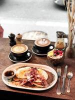 Breakfast with bacon, egg benedict and coffee on wooden table photo