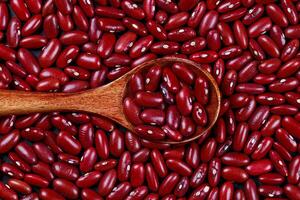 Red kidney beans in wooden spoon on black background, top view. photo