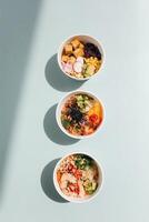 top view of delicious poke bowls with vegetables and meat isolated on blue photo