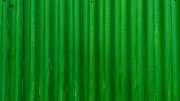 A vibrant green corrugated metal wall, displaying a simple yet striking pattern of vertical ridges and shadows. photo