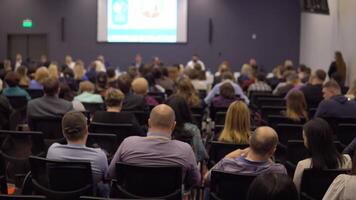 un' gruppo di persone a un' attività commerciale sviluppo addestramento. Visualizza a partire dal il indietro di il sala con persone a il conferenza. telecamera movimento giù video