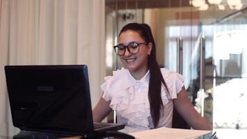 A handsome business girl is happy to clap her hands after finding out the good news in the office while sitting at the table. video