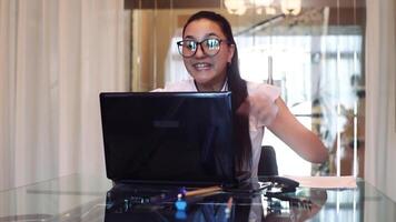 Beautiful business girl rejoices after she finds out the good news in the office while sitting at the table. video